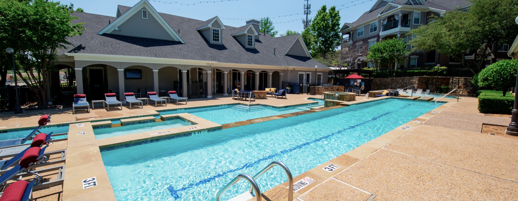 Pool area at our apartments in Grapevine, TX, featuring a hot tub and a shade structure with chairs.